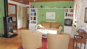 Un soggiorno con divano, due poltrone, tavolino, libreria, televisore e camino.