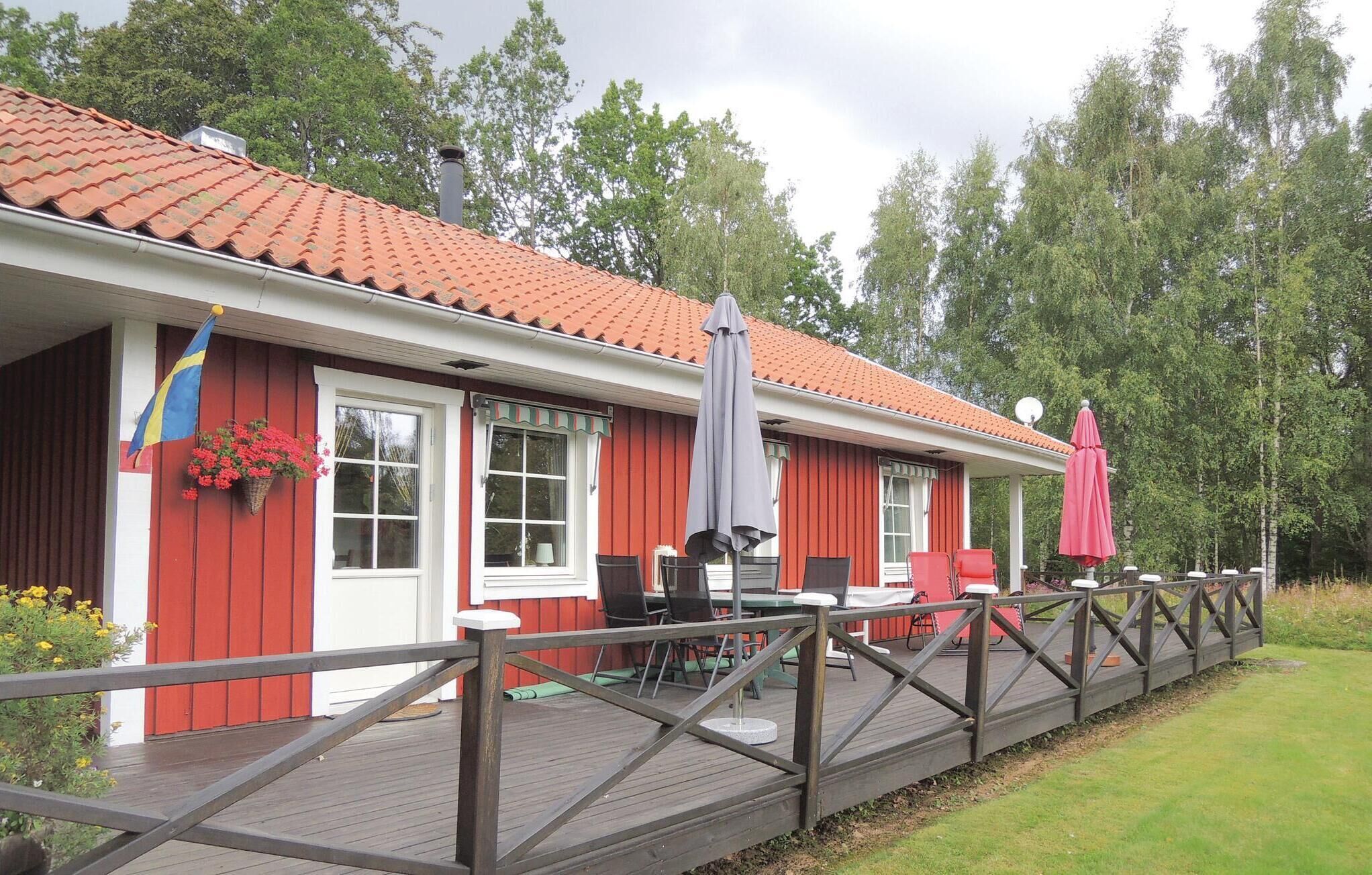 A red building with a tiled roof, a deck with outdoor furniture, and a flag.