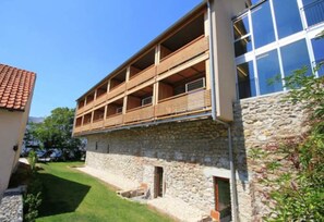 Un immeuble à plusieurs étages, doté d’une façade en pierre et de balcons en bois.