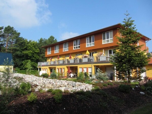 A multi-story hotel with balconies, a stone retaining wall, and a landscaped garden.