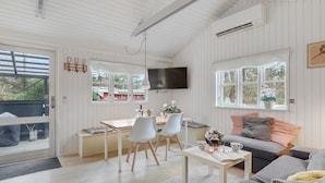 A cozy living room with a sofa, coffee table, and dining area. - Amazing home in Nexø with WiFi (Nexø)