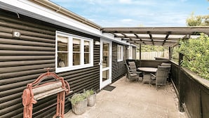 A log cabin with a patio area featuring wicker furniture and a pergola. - Amazing home in Nexø with WiFi (Nexø)