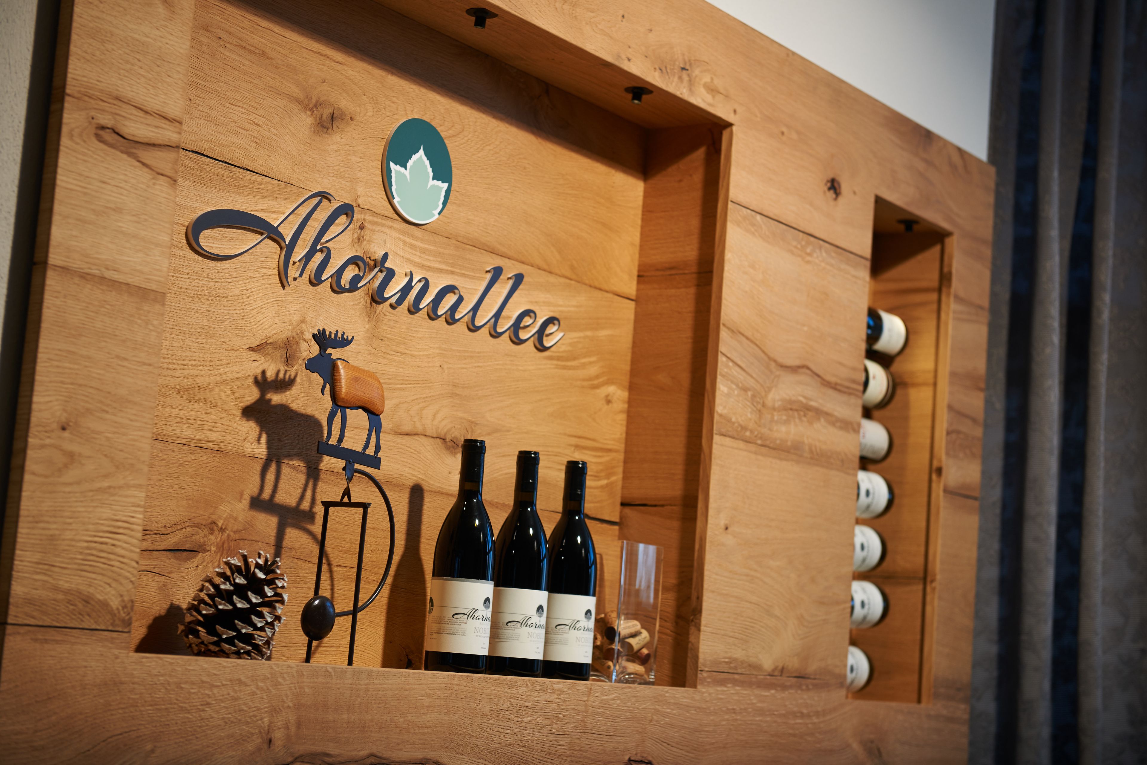 A wooden wine rack with bottles labeled "Ahornaallee" and a moose decoration.
