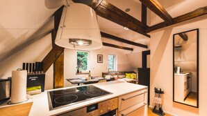Een moderne keuken met een inbouwfornuis, houten balken en een groot raam.