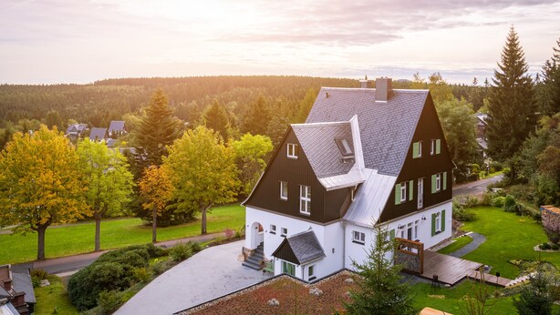 Een tweelaags huis met een schuin dak, een voortuin en een verzorgd gazon.