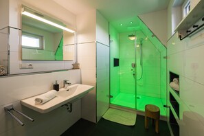 Uma casa de banho moderna com cabine de duche envidraçada, lavatório com toalha e espelho.