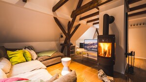 Een knus loft slaapkamer met een houten plafond, een grote televisie en een open haard.