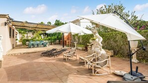 A patio with outdoor furniture, including chairs and a table, under large umbrellas.