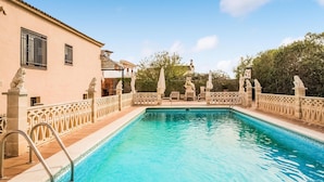 A rectangular swimming pool with a tiled edge, surrounded by a decorative fence with statues.