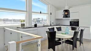 A modern kitchen with a large window, white cabinets, and a dining area with black chairs.