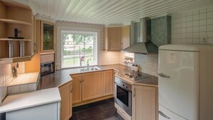 A modern kitchen with wooden cabinets, a stainless steel oven, a built-in sink, and a large window offering a view of the outdoors. - 2 bedroom nice home in ätran (Ätran)