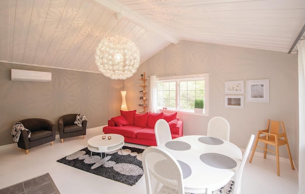 Een woonkamer met een rode bank, een witte salontafel en een kroonluchter.