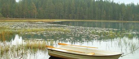 A small rowboat tied to a dock with a forested shoreline in the background.