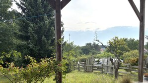 A wooden deck with a view of a fenced garden and a distant mountain.
