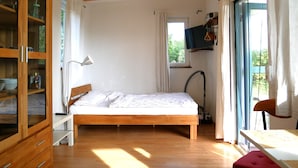 A bedroom with a wooden bed, a desk, a wardrobe, and a window with curtains.