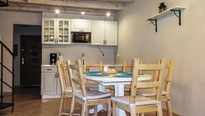 Een keuken met witte kastjes, een magnetron en een eettafel met houten stoelen.