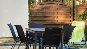 Een terras buiten met een houten omheining, een tafel en vier stoelen.
