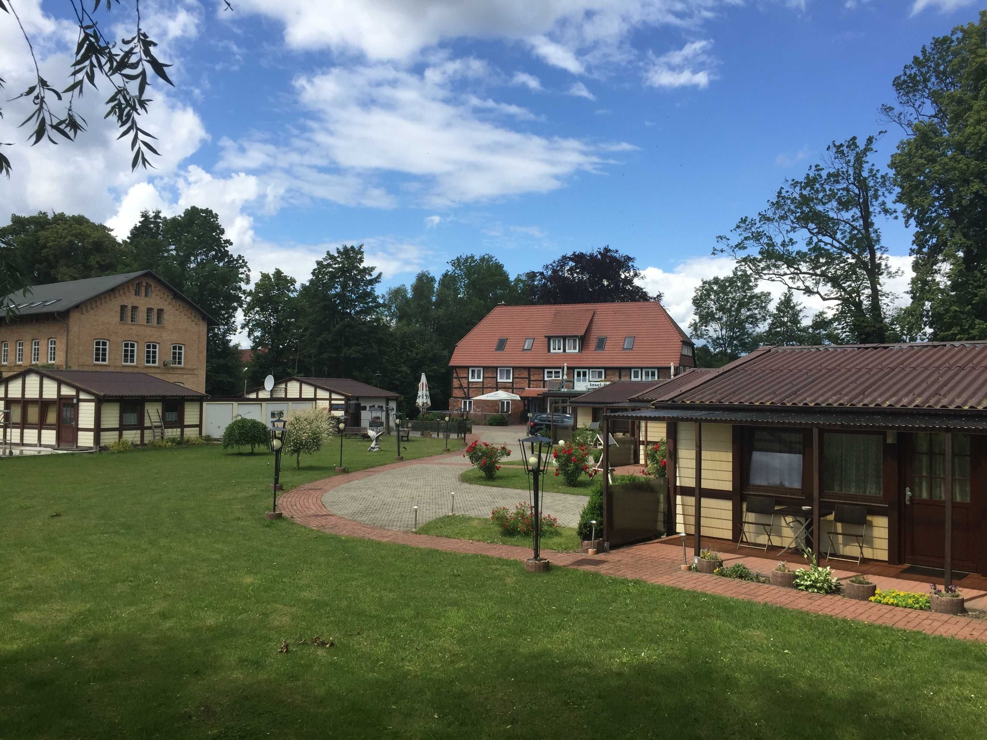A residential area with multiple houses, a paved courtyard, and a large building with a red roof.