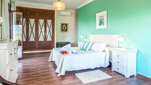 A bedroom with a bed, bedside tables, a nightstand, a dresser, a mirror, a wardrobe, and a hanging light fixture. - Stunning home in El Gastor (El Gastor)