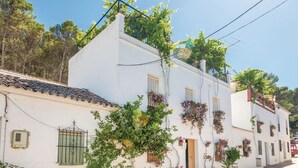 A white building with multiple windows, some with shutters, and balconies with potted plants. - Stunning home in El Gastor (El Gastor)