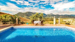 A swimming pool with a view of mountains and a patio area with chairs and a table. - Stunning home in El Gastor (El Gastor)