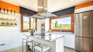 A modern kitchen with a central island, stainless steel appliances, and large windows offering a view of the outdoors. - Stunning home in Mancor de la Vall (Mancor de la Vall)