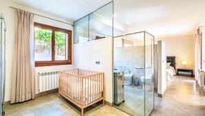 A modern bathroom with a glass shower enclosure, a wooden crib, and a view of the outdoors through a window. - Stunning home in Mancor de la Vall (Mancor de la Vall)