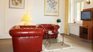 Un soggiorno con un divano in pelle rossa, un tavolino in vetro e una televisione su un mobile in legno.
