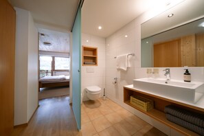A modern bathroom with a large sink, toilet, and a wooden cabinet.