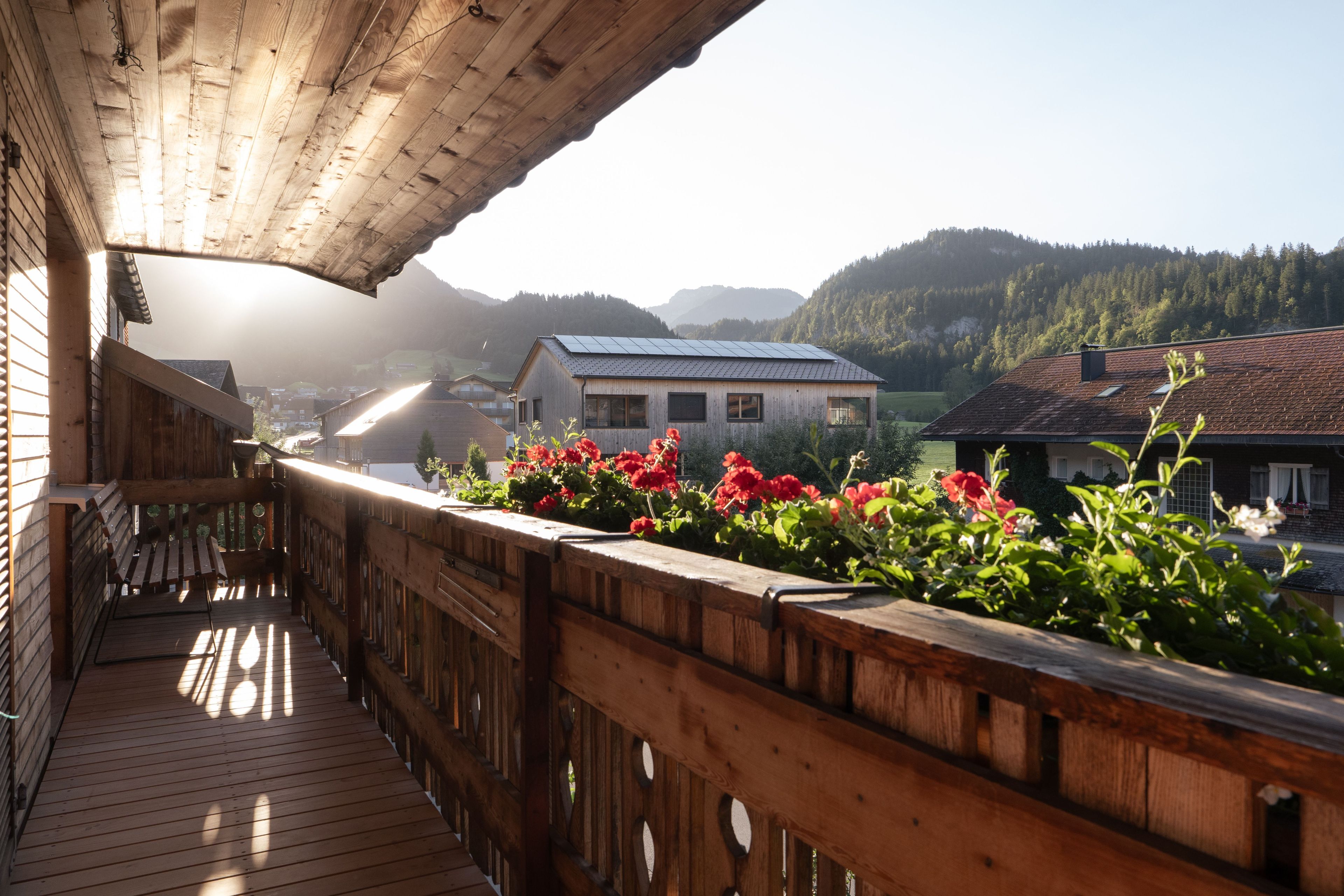 A wooden balcony with a view of a village and mountains.