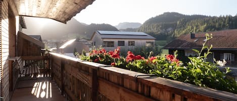 Un balcón de madera con vistas a un pueblo y montañas.