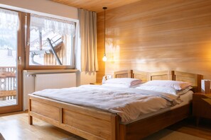 A wooden bed with a headboard, a nightstand, and a window with curtains.