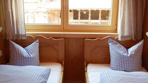 Quarto com duas camas, cada uma com roupa de cama xadrez e cabeceiras de madeira.
