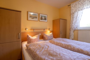 Une chambre avec deux lits, une armoire en bois et une fenêtre avec des rideaux.