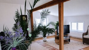 A living room with a wooden ceiling, a television, a sofa, and several potted plants. - Apartment Ivan (2nd floor) - Ivan Apartments - Property 26001 (Rostock)