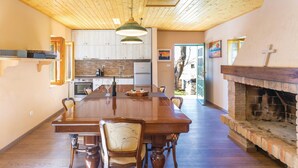 Un comedor amplio con una larga mesa de madera, rodeado de sillas, y una chimenea a la derecha.