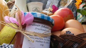 A jar of fruit jam with a label, surrounded by eggs and a wicker basket.