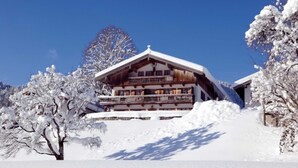 A wooden chalet with multiple balconies, surrounded by snow-covered trees. - Apartment Blauberg - Böcklhof, Kreuth-Brunnbichl (Kreuth)