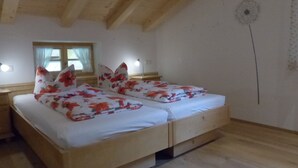 A room with a wooden ceiling, a bed with floral bedding, a window with curtains, and a wall with a dandelion illustration. - Apartment Blauberg - Böcklhof, Kreuth-Brunnbichl (Kreuth)