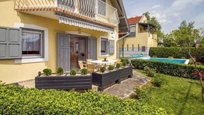 Una casa de dos pisos con balcón, piscina y un jardín bien cuidado.