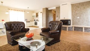 Una sala de estar moderna con dos sillones de cuero, una mesa de centro de vidrio y una chimenea.