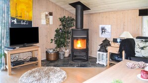 Ein gemütliches Wohnzimmer mit Kaminofen, Flachbildfernseher und einer bequemen Sitzecke.