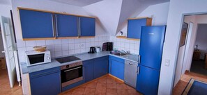 A compact kitchen with blue cabinets, a microwave, a toaster, and a dishwasher.