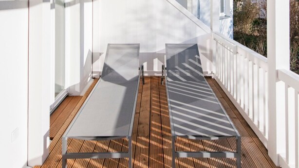A covered outdoor area with two sun loungers, wooden flooring, and a white railing. - Apartment 01 - "Villa Minerva" Apartment 01 (Kühlungsborn)