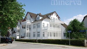 A multi-story hotel with balconies, a clear sky, and a sign indicating directions. - Apartment 01 - "Villa Minerva" Apartment 01 (Kühlungsborn)