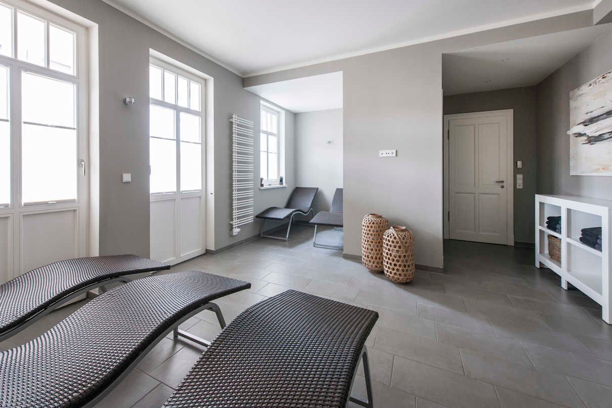 Una habitación amplia con dos sillones, una zona de estar con un banco, un radiador y un armario blanco con estantes.