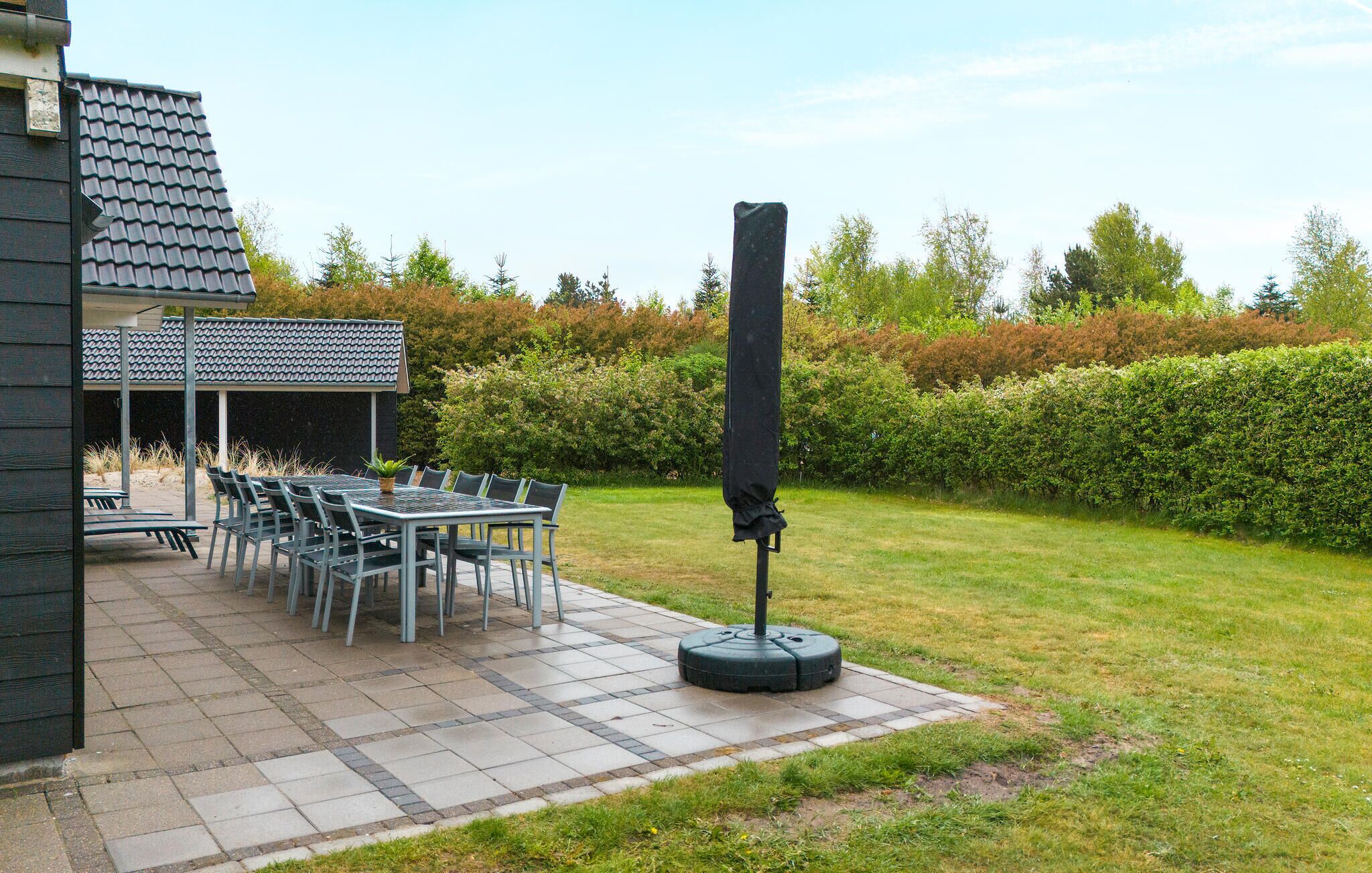 A patio area with a table and chairs, a covered seating area, and a large black object on a circular base.