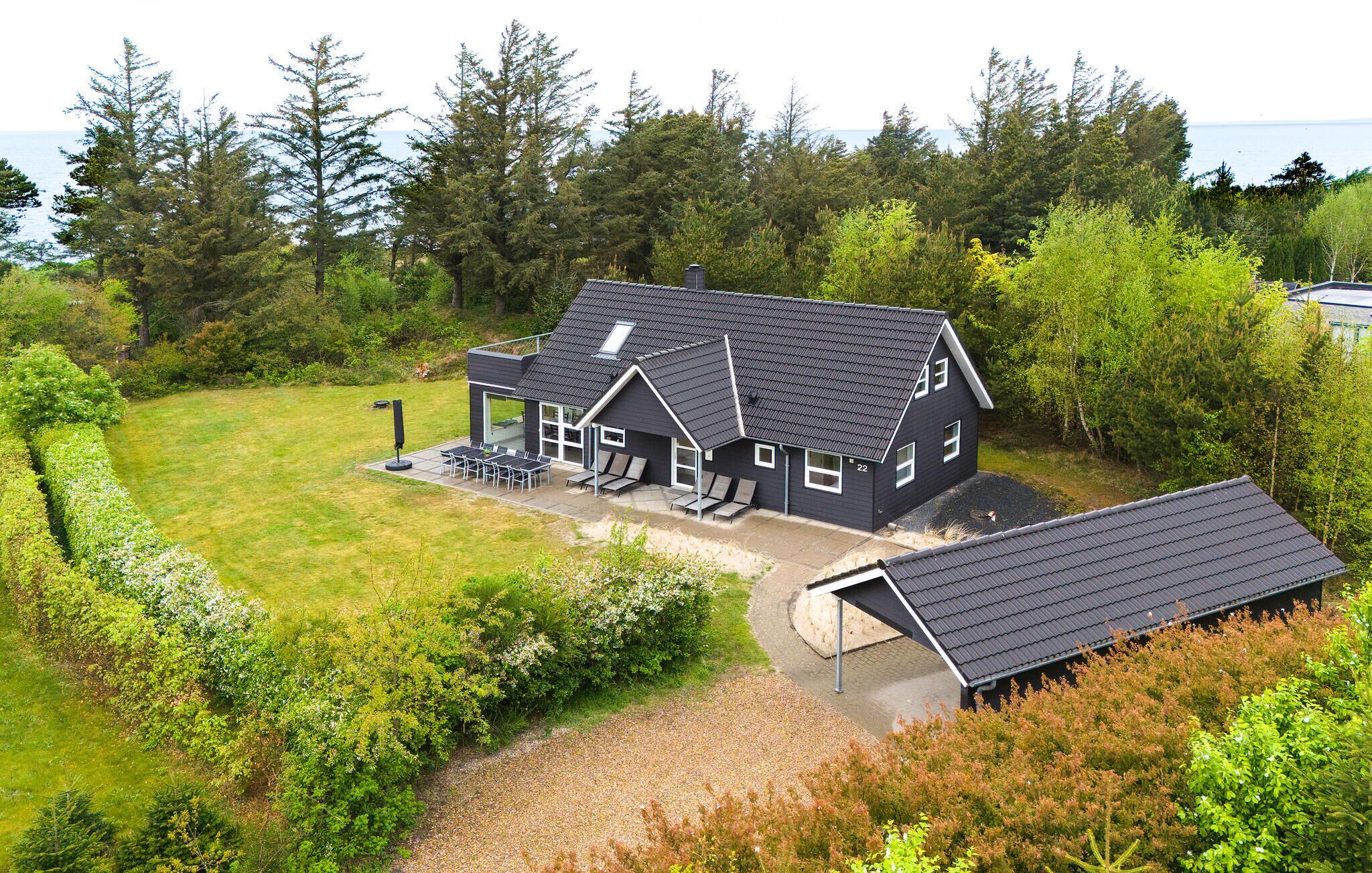A modern two-story house with a covered patio and a view of the sea.