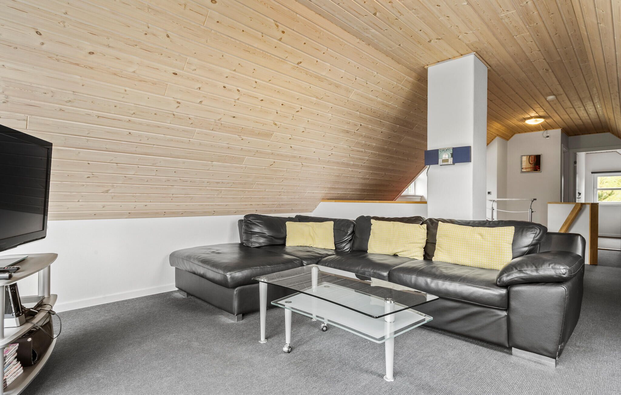 A modern living room with a sectional sofa, a glass coffee table, and a flat-screen TV.