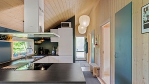 A modern kitchen with a central island, a microwave, and a coffee maker. - Nice home in Væggerløse with sauna (Væggerløse)